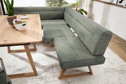 Eckbank in modernem Design mit grauem Stoffbezug und Holzbeinen, neben einem Esstisch aus Holz, aus der Perspektive von schräg oben fotografiert.
