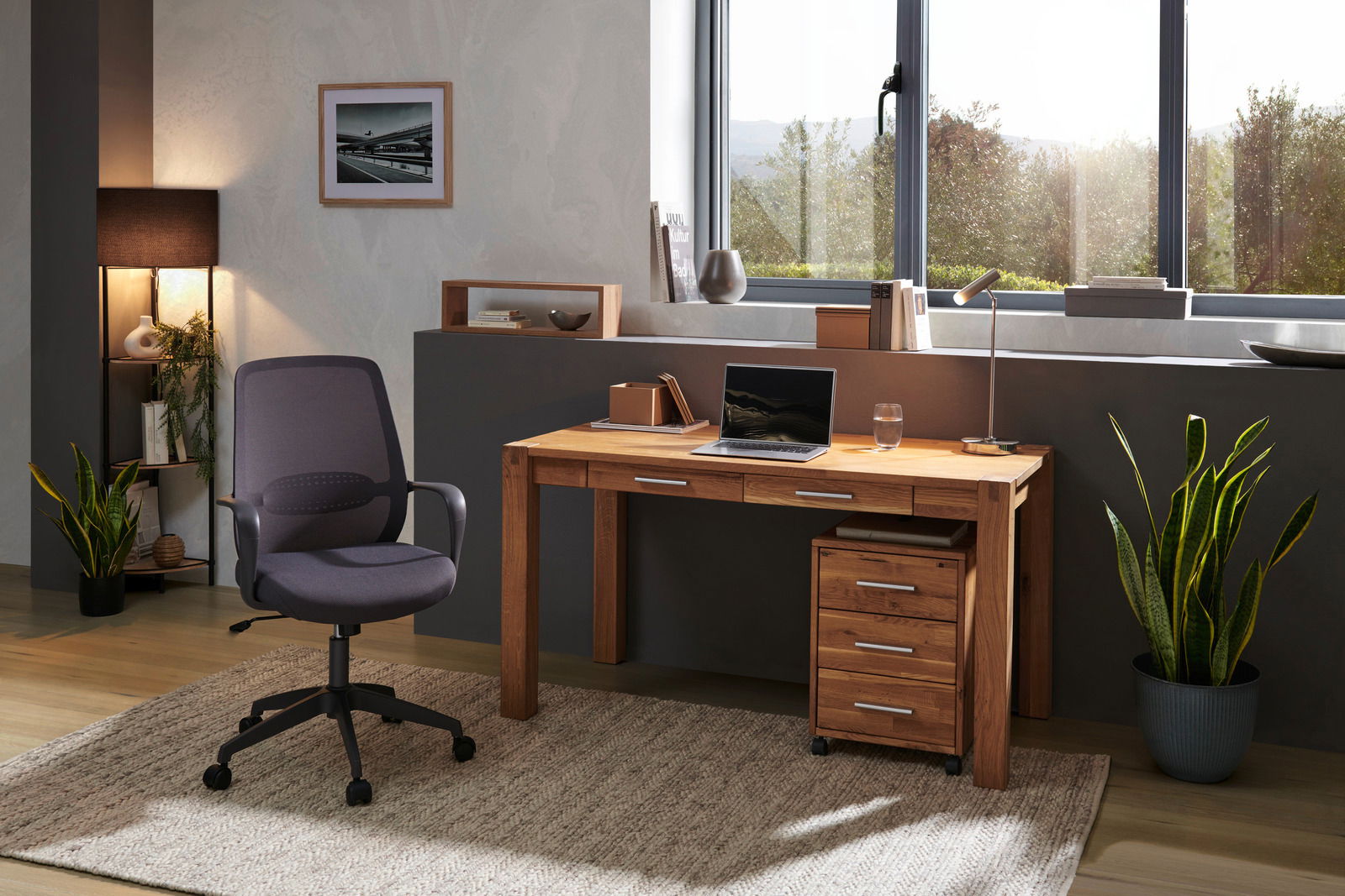 Moderner Schreibtisch aus Holz mit Schubladen, Laptop und Lampe, seitliche Perspektive