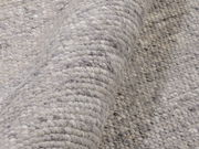 Nahaufnahme eines handgewebten Teppichs in Grautönen, der eine detaillierte Ansicht der Textur und Webart zeigt.
