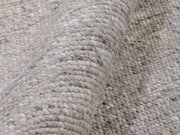 Nahaufnahme eines handgewebten Teppichs in Grautönen, der eine detaillierte Ansicht der Textur und Webart zeigt.