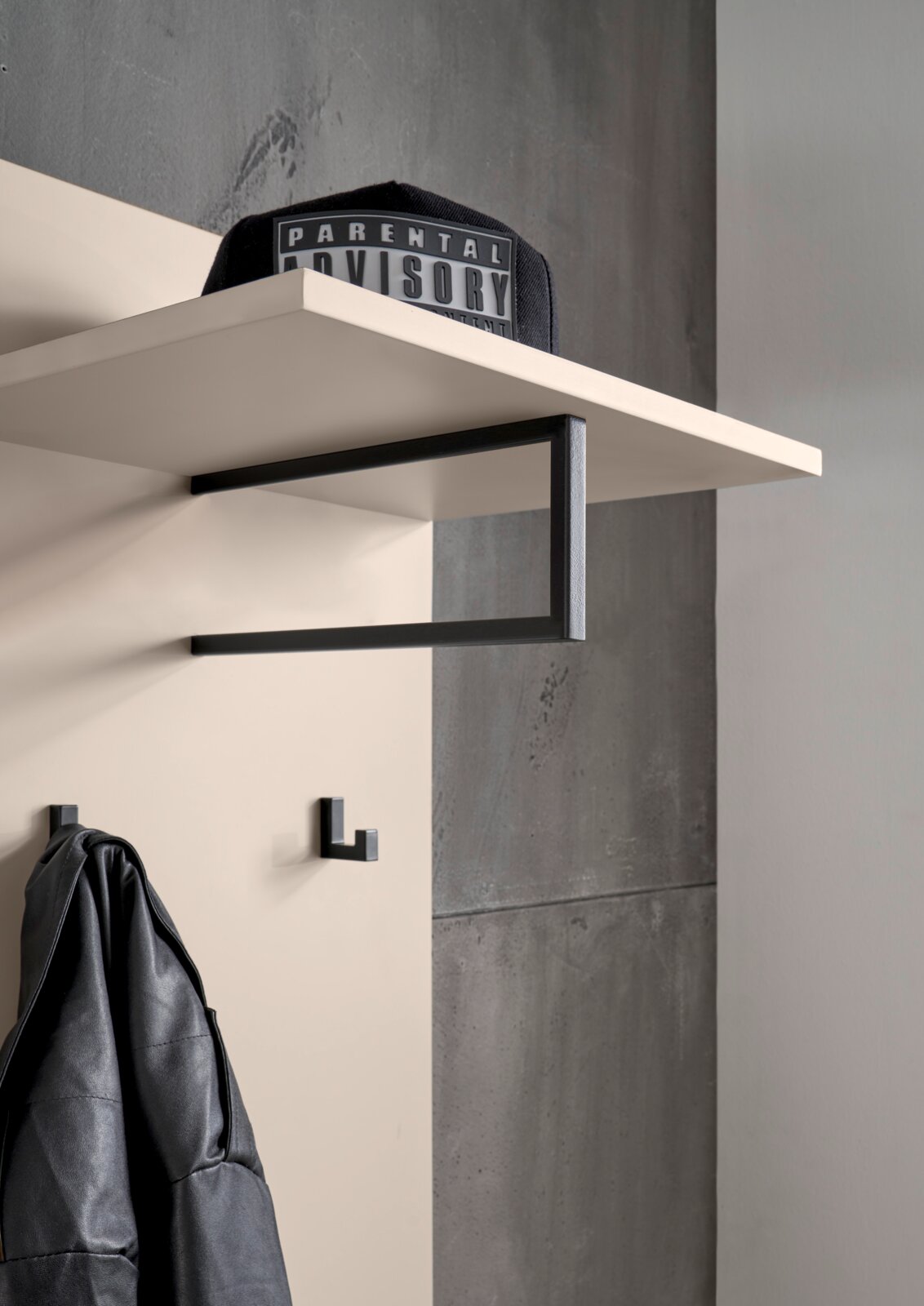 Moderne Wandgarderobe mit weißem Ablagebrett und schwarzem Metallrahmen, darunter Haken; schräg von unten aus der Seitenperspektive fotografiert