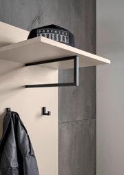 Moderne Wandgarderobe mit weißem Ablagebrett und schwarzem Metallrahmen, darunter Haken; schräg von unten aus der Seitenperspektive fotografiert