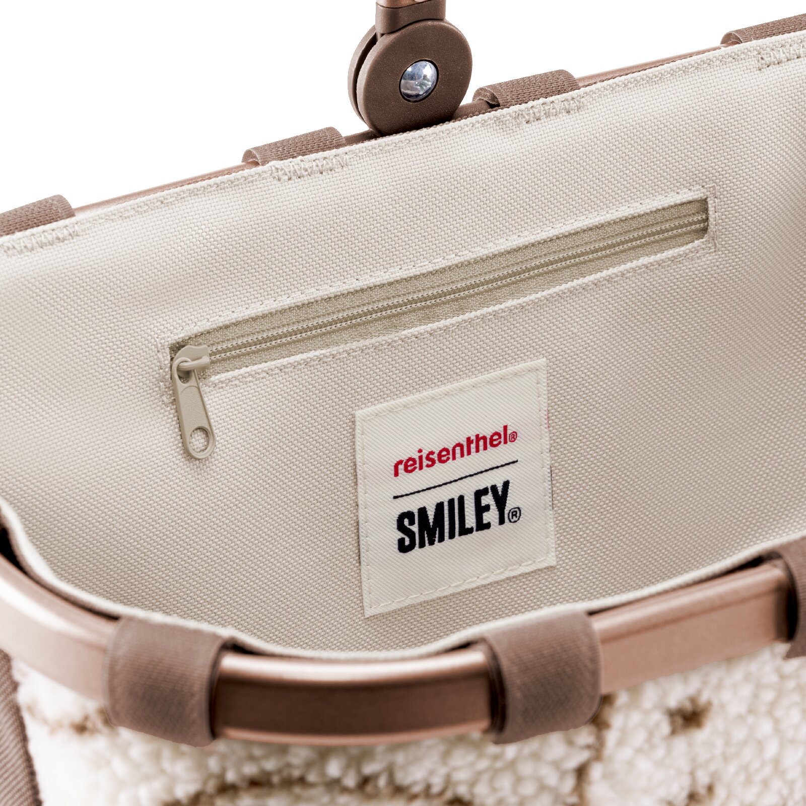 Close-up vanuit bovenaanzicht van de beige binnenzijde van een reisenthel SMILEY-tas met praktisch ritsvak en merklabel.