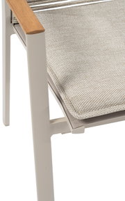 Nahaufnahme eines Stapelsessels mit hellem Polster und Armlehne aus Holz, seitliche Perspektive