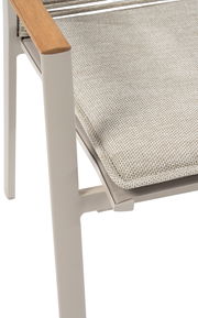 Nahaufnahme eines Stapelsessels mit hellem Polster und Armlehne aus Holz, seitliche Perspektive