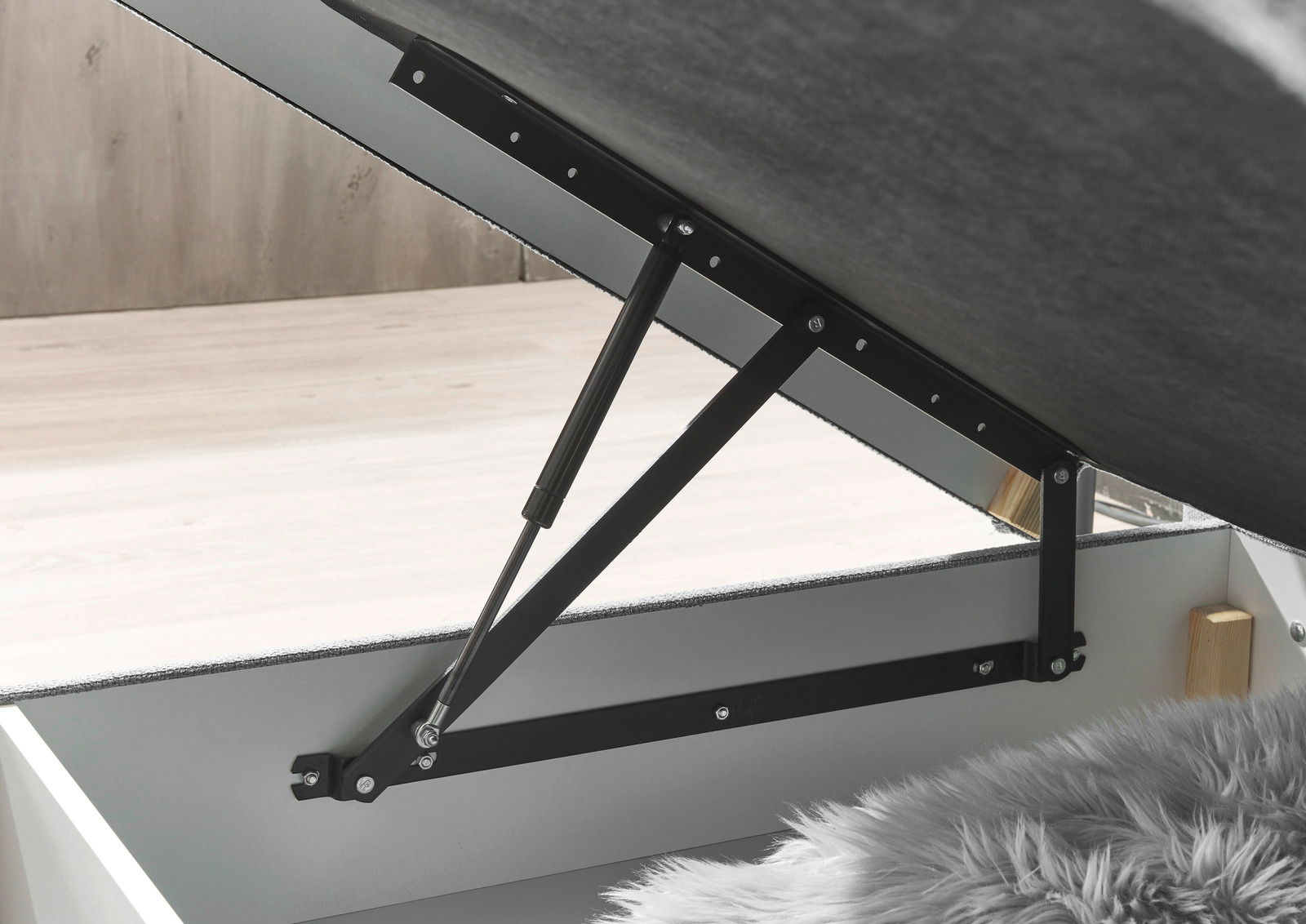 Nahaufnahme eines geöffneten Boxspringbetts mit hydraulischem Hebemechanismus, seitliche Perspektive.