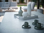 Modernes Tablett in einem stilvollen Außenbereich, mit drei dekorativen Vasen darauf, aus einer seitlichen Perspektive fotografiert.