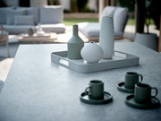 Modernes Tablett in einem stilvollen Außenbereich, mit drei dekorativen Vasen darauf, aus einer seitlichen Perspektive fotografiert.