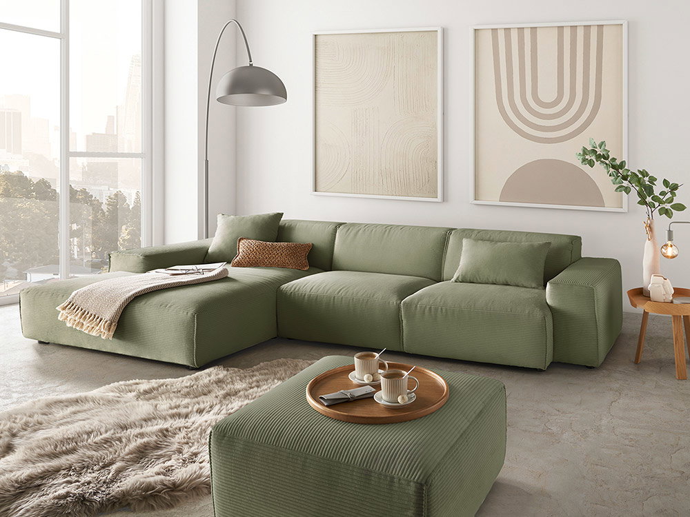 Modernes Cordsofa in Salbeigrün, umgeben von natürlichen Beigetönen und braune Sofakissen als Farbakzent