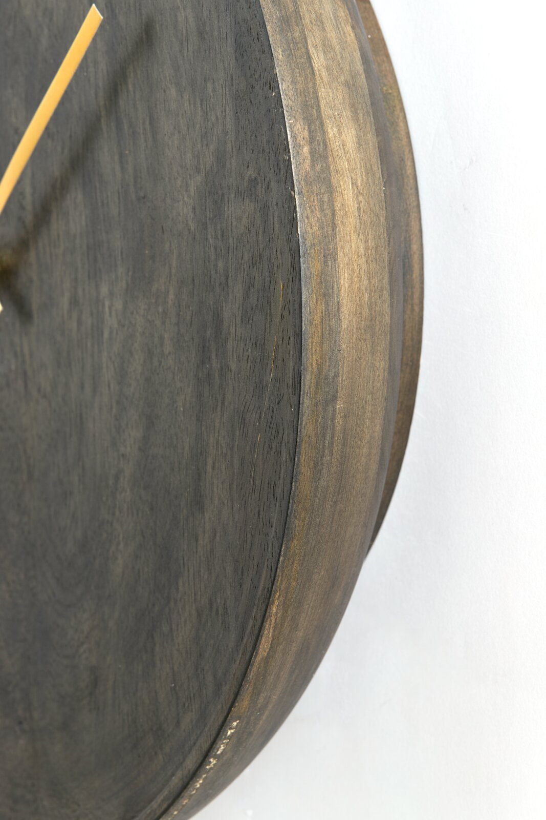 Close-up van een houten klok vanuit een zijdelingse hoek, waarop de textuur en de rand van de wijzerplaat te zien zijn.