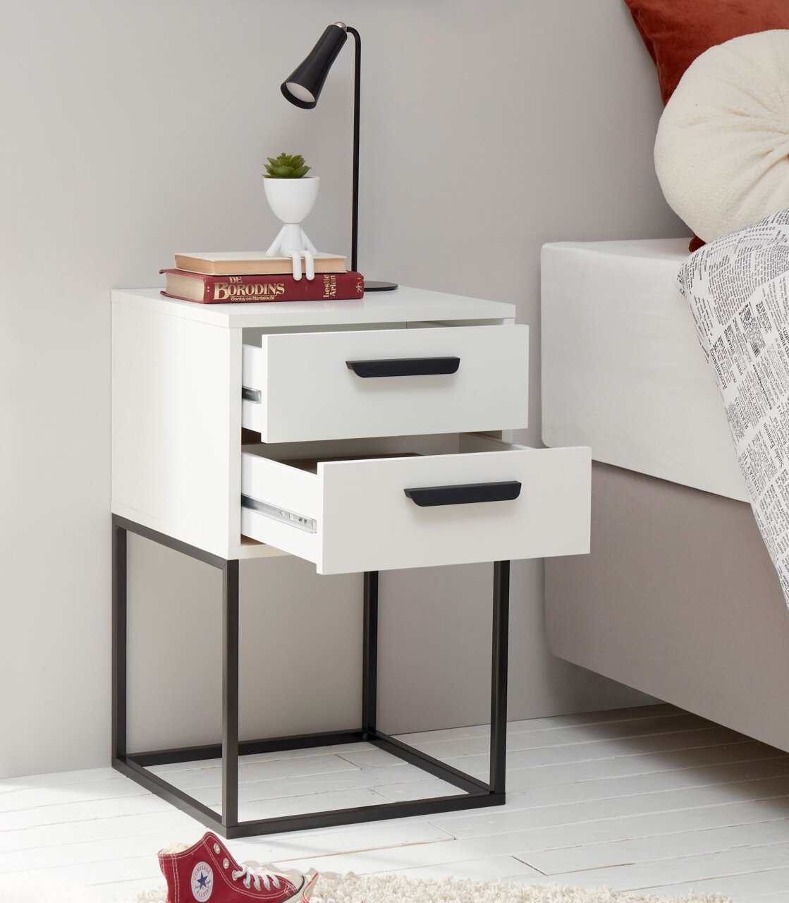 Moderne Nachtkommode mit zwei offenen Schubladen, schwarzem Metallrahmen und Dekorationen, seitliche Perspektive