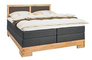 Boxspringbett mit Holzrahmen und grauem Stoffbezug, seitliche Perspektive