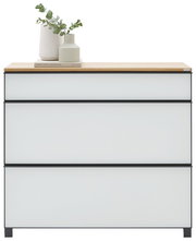 Moderne Kommode mit drei grifflosen Schubladen, hellgrauen Fronten und schwarzem Rahmen sowie Holzplatte, dekoriert mit Vase und Eukalyptus; Frontansicht auf weißem Hintergrund.