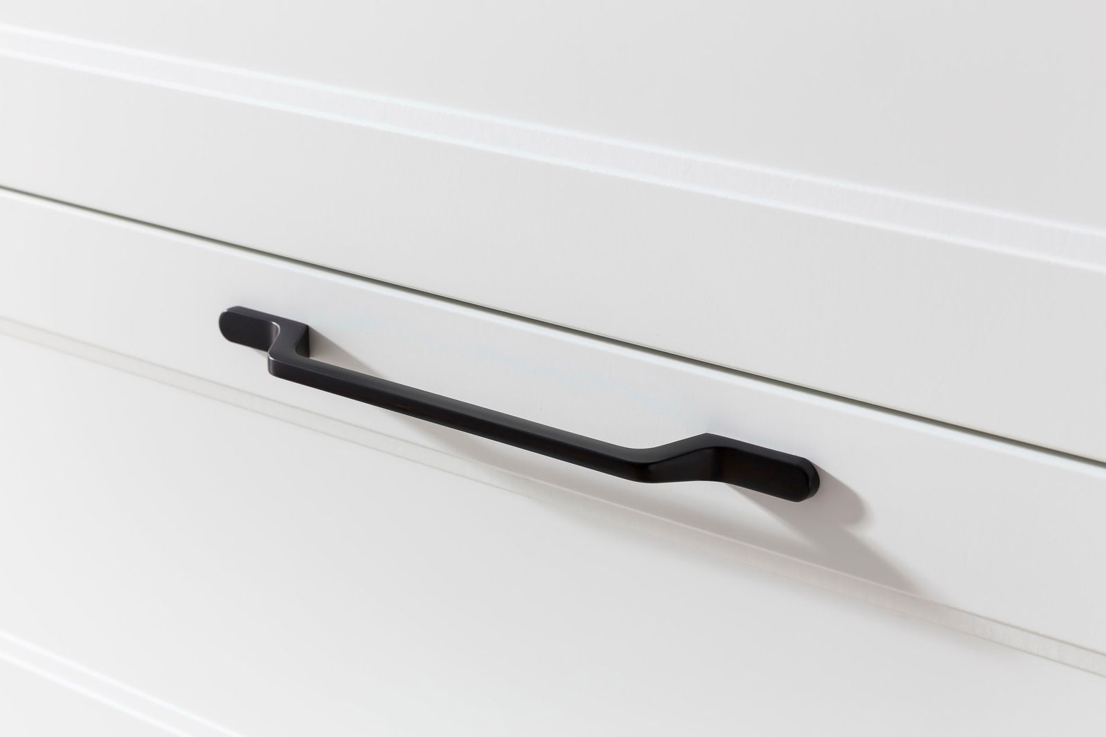 Nahaufnahme eines schwarzen Griffs an einer weißen Schublade, seitliche Perspektive