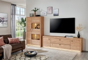 Modernes Wohnzimmer mit TV-Lowboard und Vitrine aus hellem Holz mit integrierter Beleuchtung, frontal aus leicht schräger Perspektive aufgenommen