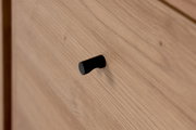 Nahaufnahme eines Holz-Sideboards mit schwarzem Griff, seitliche Perspektive