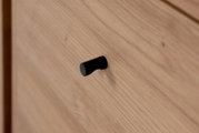 Nahaufnahme eines Holz-Sideboards mit schwarzem Griff, seitliche Perspektive