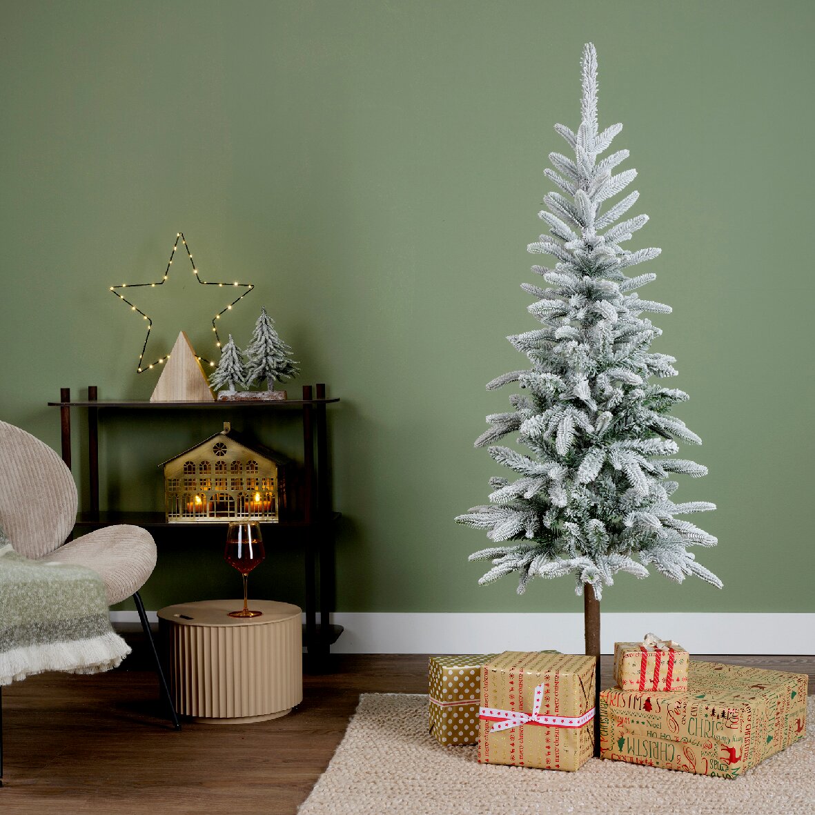 Künstlicher Weihnachtsbaum mit Schneeoptik, dekoriert in einem modernen Wohnzimmer mit Geschenken und festlicher Beleuchtung, seitliche Perspektive