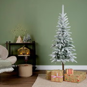Künstlicher Weihnachtsbaum mit Schneeoptik, dekoriert in einem modernen Wohnzimmer mit Geschenken und festlicher Beleuchtung, seitliche Perspektive