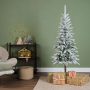 Künstlicher Weihnachtsbaum mit Schneeoptik, dekoriert in einem modernen Wohnzimmer mit Geschenken und festlicher Beleuchtung, seitliche Perspektive