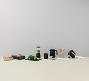 FOODIE Flachtoaster in Schwarz, frontal auf einem Tisch mit anderen Küchengeräten und Zutaten arrangiert.