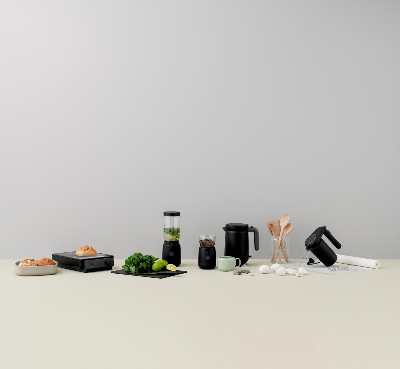 FOODIE Flachtoaster in Schwarz, frontal auf einem Tisch mit anderen Küchengeräten und Zutaten arrangiert.