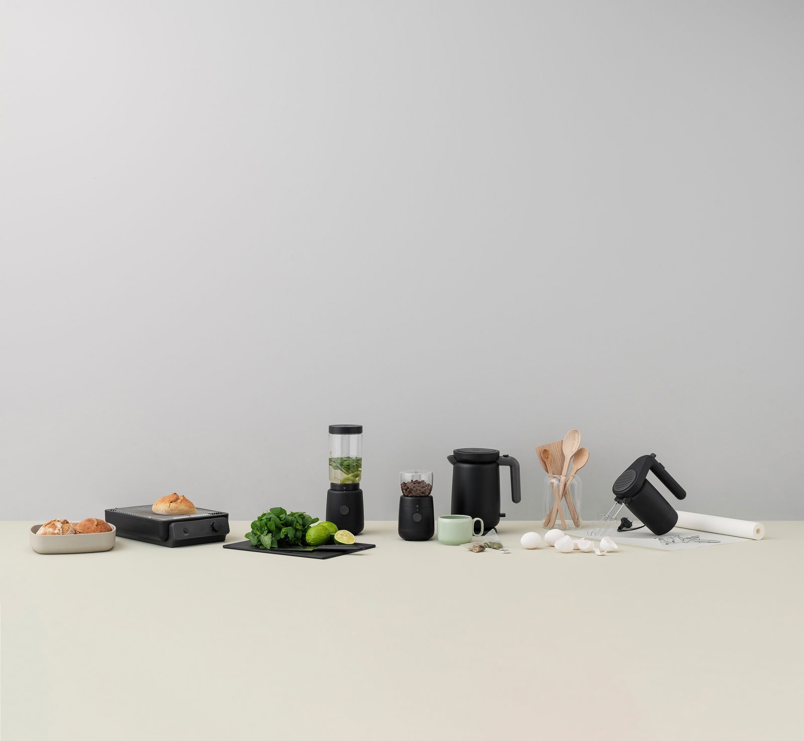FOODIE Flachtoaster in Schwarz, frontal auf einem Tisch mit anderen Küchengeräten und Zutaten arrangiert.
