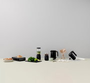 FOODIE platte broodrooster in het zwart, vooraan op een tafel neergezet naast andere keukenapparaten en ingrediënten.