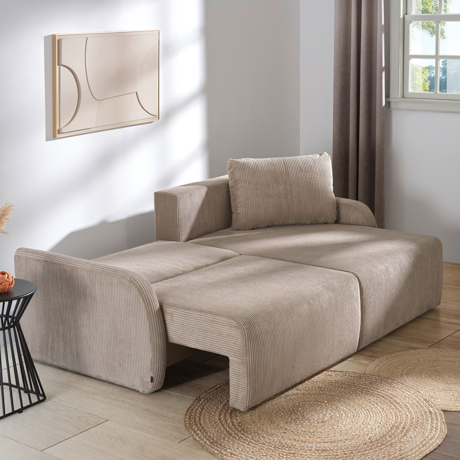 Beiges Ecksofa JENIFER in einem modernen Wohnzimmer, seitliche Perspektive, mit Kissen und dekorativem Wandbild.