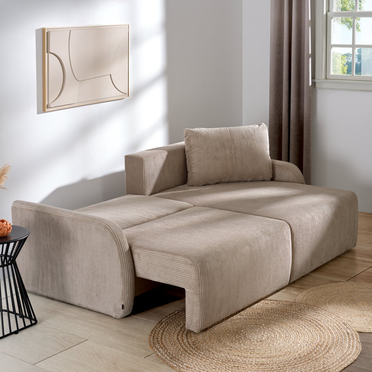 Beiges Ecksofa JENIFER in einem modernen Wohnzimmer, seitliche Perspektive, mit Kissen und dekorativem Wandbild.