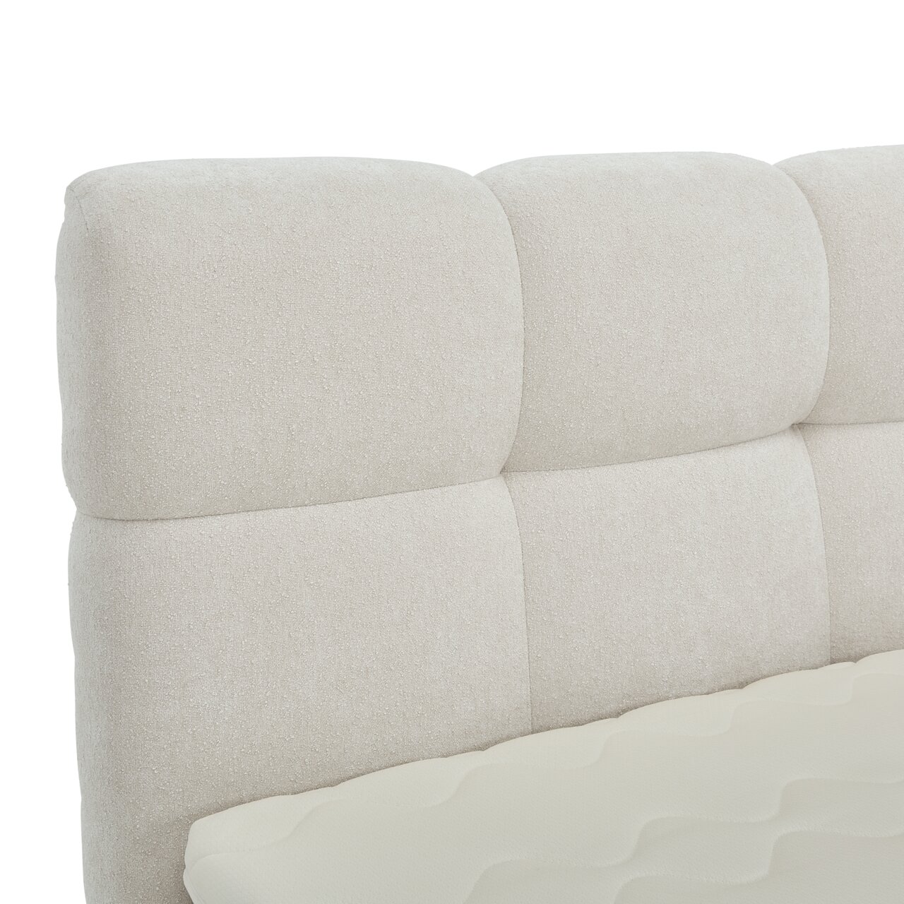 Nahaufnahme eines gepolsterten, cremefarbenen Boxbett-Kopfteil mit weicher Textur, seitliche Perspektive