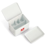 Offene weiße Medizinbox mit Fächern, Deckel daneben liegend, aus der Vogelperspektive.