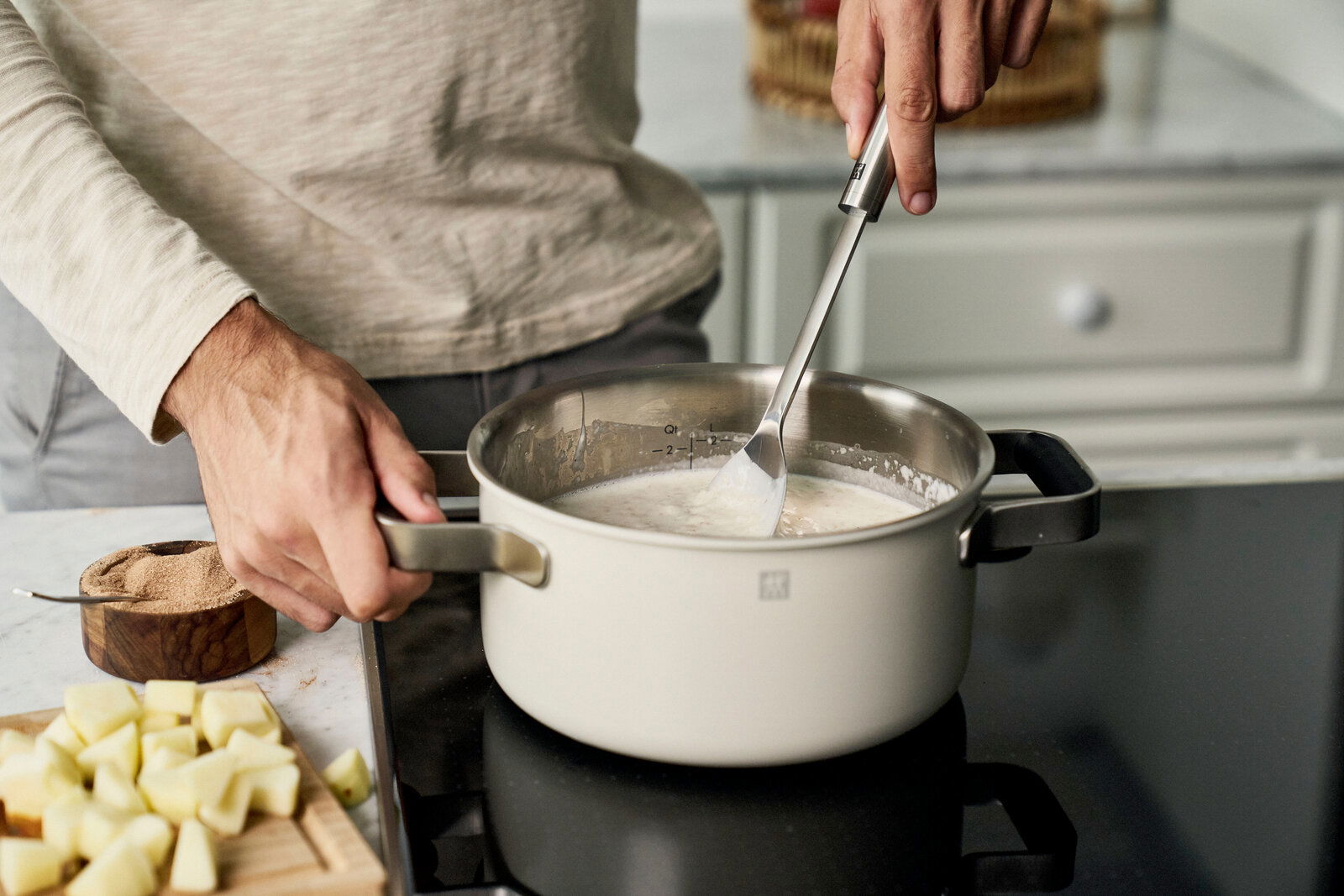 Mann rührt in einem Topf auf einem Herd, seitliche Perspektive