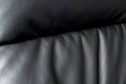 Nahaufnahme der schwarzen Lederpolsterung eines Chefsessels, von vorne betrachtet.
