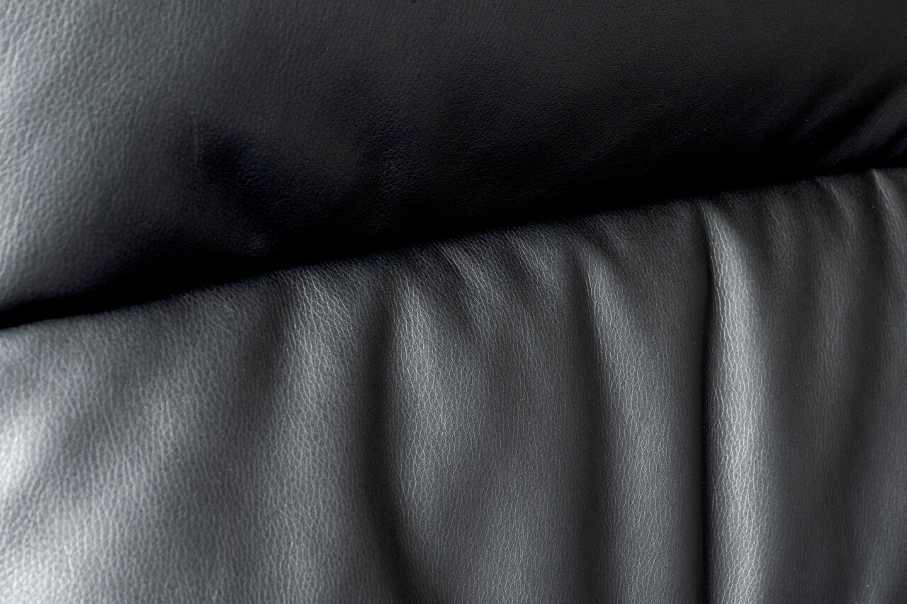 Close-up van de zwarte lederen bekleding van een directiestoel, gezien vanaf de voorkant.