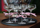 Edle Sektgläser mit rosa Schleifen auf schwarzem Serviertablett – elegante Tischdekoration für festliche Anlässe
