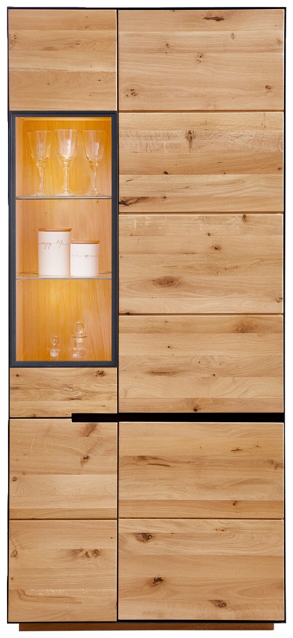 Vitrine met verlichting van hout, gefotografeerd vanaf de voorkant, met glazen deuren en decoratieve glazen voorwerpen binnenin.