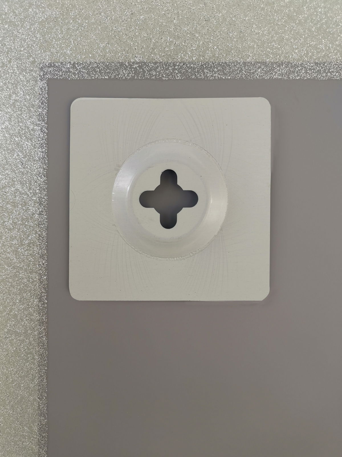 Nahaufnahme der Rückseite eines Spiegels mit einer Wandhalterung, silberner Rahmen sichtbar.