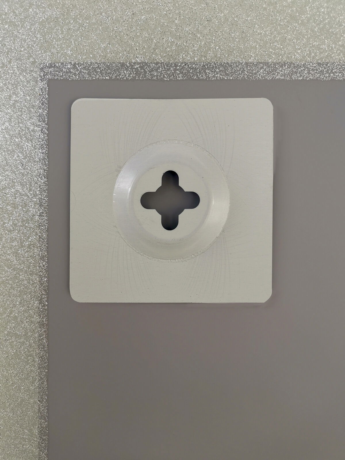 Nahaufnahme der Rückseite eines Spiegels mit einer Wandhalterung, silberner Rahmen sichtbar.