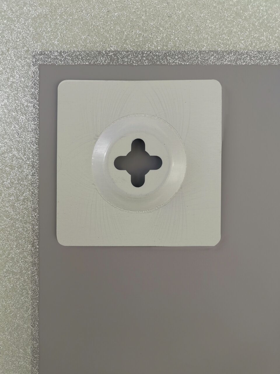 Nahaufnahme der Rückseite eines Spiegels mit einer Wandhalterung, silberner Rahmen sichtbar.