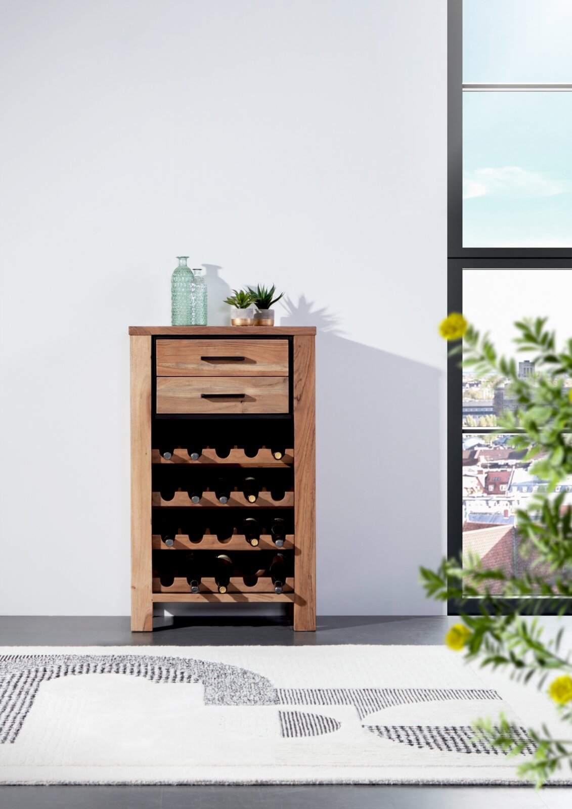 Weinregal aus Holz mit mehreren Ebenen zur Lagerung von Weinflaschen, frontal fotografiert. Auf der Oberseite stehen dekorative Glasflaschen und Pflanzen.