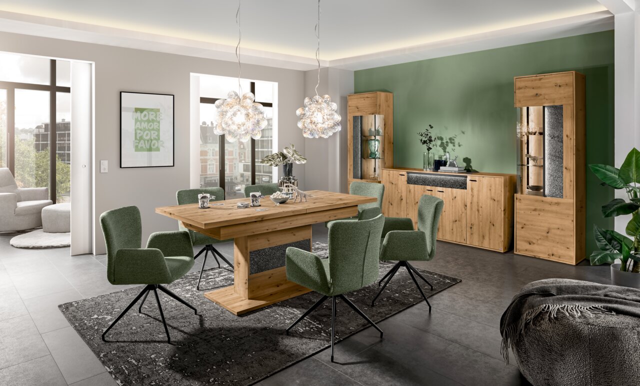 Set one by Musterring Funktions-Esstisch DELTONA Moderner Funktions-Esstisch aus Holz in einem stilvollen Esszimmer mit grünen Stühlen und hängenden Lampen, seitliche Perspektive.