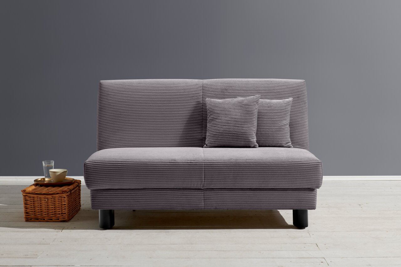Z2 Schlafsofa ENNY Graues Funktionssofa mit zwei Kissen, frontal fotografiert, auf hellem Holzboden vor grauer Wand.