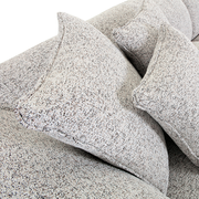 Nahaufnahme von einem Big-Sofa mit strukturiertem Stoffbezug und mehreren großen Kissen, seitliche Perspektive