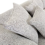 Nahaufnahme von einem Big-Sofa mit strukturiertem Stoffbezug und mehreren großen Kissen, seitliche Perspektive