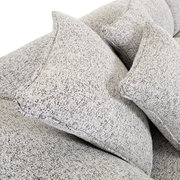 Nahaufnahme von einem Big-Sofa mit strukturiertem Stoffbezug und mehreren großen Kissen, seitliche Perspektive