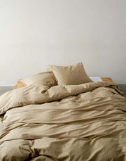Beige Bettwäsche-Set auf einem Bett, fotografiert aus einer frontalen Perspektive.