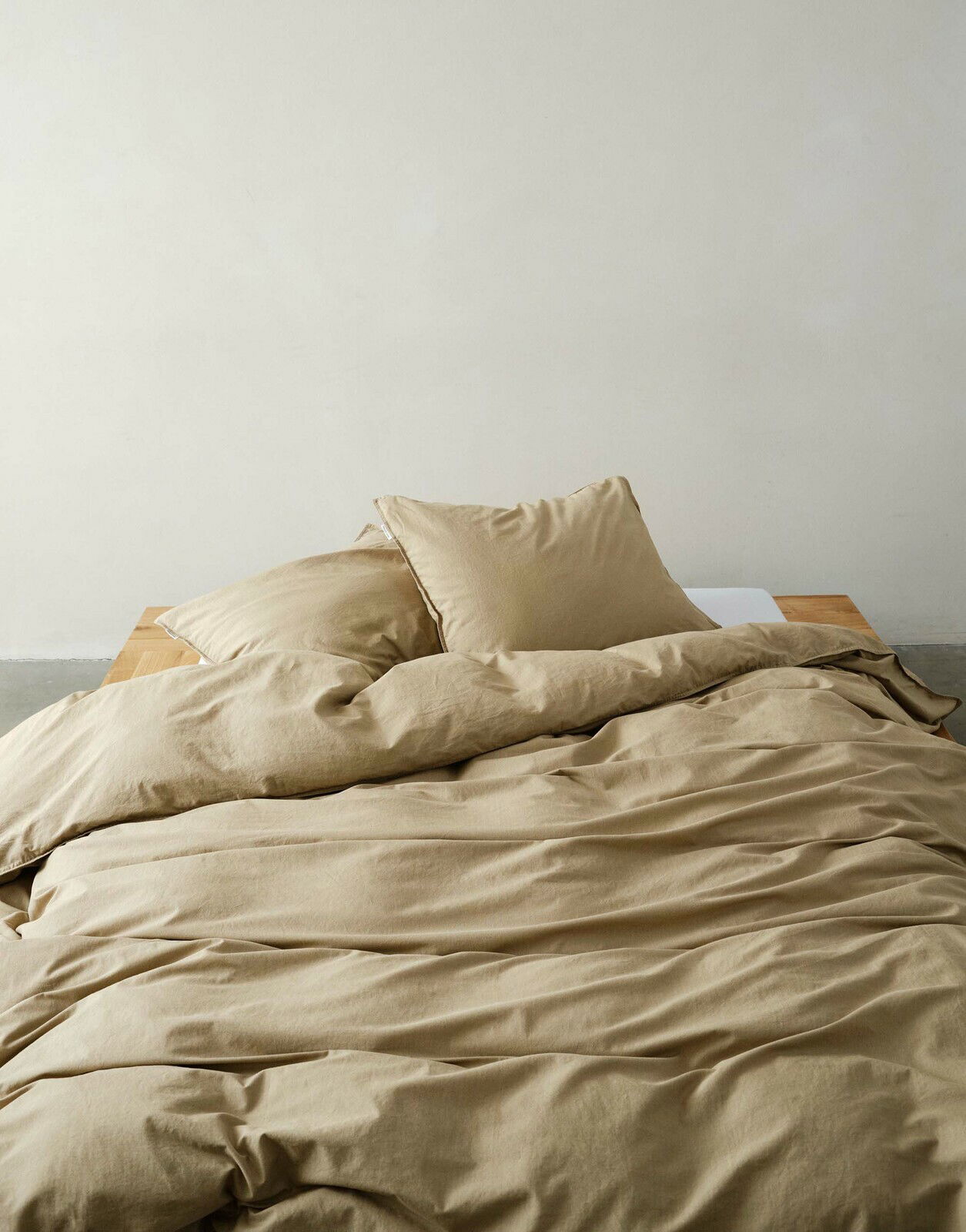 Beige Bettwäsche-Set auf einem Bett, fotografiert aus einer frontalen Perspektive.