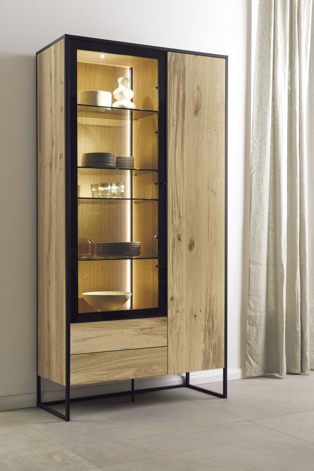 Moderne Vitrine aus Holz mit Glastüren, beleuchtetem Innenraum und Metallrahmen, seitliche Perspektive.