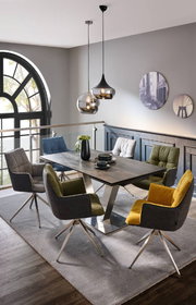 Moderner Esstisch mit Metallgestell und Holzplatte, umgeben von bunten Stühlen in einem stilvollen Esszimmer mit Blick auf ein großes Fenster.